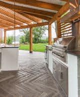 The covered outdoor kitchen features chef grade appliances including a built in grill with hood, warming drawers, refrigeration and disposal 