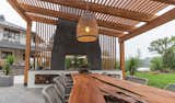 The custom pergola transitions to a shade structure over the outdoor dining room and culminates in a double sided, dyed stucco fireplace with built in wood storage below 