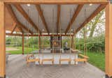 The covered outdoor kitchen features custom timber swing seating around the bar