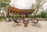 The custom pergola sits on a larger patio with a fire pit and multiple lounge areas 