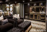 The theatre was designed for this movie lover family to be plush, lush and edgy with an Art Deco vibe as a nod to old Hollywood. Upholstered paneled walls with millwork design inserts play a glamorous foil to the rich chocolate custom cabinetry, gold accents and oversized chocolate velvet seating.