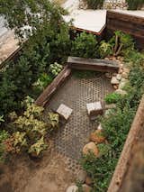 The yard feels secluded thanks to solid fencing and a buffer of dense greenery. Benches by Angel City Lumber, stacked on stones and all from Molly’s home state of Oregon, create a seating moment to look back at a towering cork oak tree. The pavers and Adirondack chairs are all from OR.CA