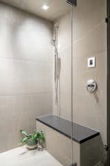 The double head shower & steam room: A secondary hand held shower hangs above the concrete topped bench, as does the steam shower control. The back shower wall features a textured/3D tile that is highlighted by wall wash recessed lighting above.