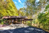 Outdoor, Woodland, Stone Fences, Wall, Large Patio, Porch, Deck, Trees, Shrubs, Concrete Fences, Wall, Stone Patio, Porch, Deck, and Hardscapes The view of the house from the driveway.  Photo 8 of 17 in The Barrett-Tuxford House by William Green