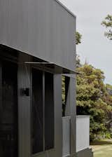 Galvanised steel plate canopies add a subtle shimmer to the dark façade