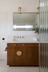 Primary bathroom with medium wood vanity and gold hardware