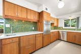 Leveraging the original kitchen layout, the owners applied new cabinet veneers to the original cabinetry surrounding the 1958 General Electric stove. Italian glass mosaic tile and vintage lighting fixtures add that special touch. Refrigerator drawers replace the bulking appliance to free up the space.