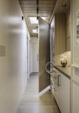 View down hallway showing laundry area with built-in stacked washer/dryer.  Door to this cabinet hinges open the slides back into pocket beside appliances.  