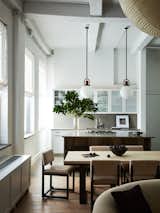 Another view of the kitchen featuring the shearling and leather dining chairs, white oak dining table and pendants over the island by Allied Maker. 