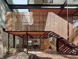 The homeowners agreed to include a floating staircase—suspended from structural steel to avoid tree roots—which allows visitors to access the second-floor terrace and bedroom from the courtyard.