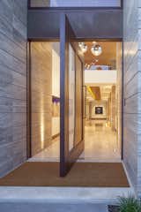 As one enters the home, they are greeted by the limestone floors and columns, the art gallery, and the brightly lit space in the foyer. The pivot door is ideal when guests are coming into the home, as it can be left open, creating an ample and inviting space for people to walk in.  Photo 6 of 15 in Encinitas Surf Retreat by Victoria Velasco Celaya