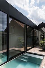 The extension has black cladding and a M shaped gable roof that becomes a regular gable roof towards the back of the extension.