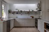 After: The U-shaped kitchen has MDF cabinetry and shelving, and two sinks allow the homeowners to undergo multiple tasks at once (washing vegetables, thawing frozen items, filling pots). A light well over the open shelving helps brighten the room. 