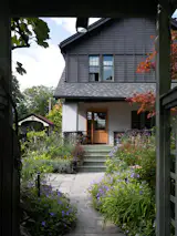 After: The front porch feels fresh and streamlined with a new unfinished wood door and minimal railings. 