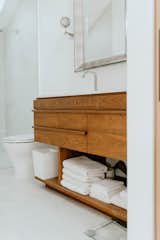 The bathroom that survived the fire is one that interior designer Dawn Kirker helped renovate nearly a decade before. The floating walnut vanity brings warmth to the otherwise white-toned room. 
