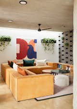 A painting by architect Gregory Katz adds vibrant color to the living room. The sofa and tables are from Up-Cycled, a company that upholsters, refurbishes, and makes custom furniture. The geometric, gray-and-black wall is made with bricks from Corobrik, a South African brick manufacturer.