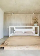 In the primary bedroom, a wall of melamine closets looks and feels like wood. The bed—which has a concrete headboard and cottonwood frame—is made by a local company, Homewood, that specializes in up-cycling invasive wood and plant species into furniture.
