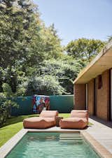 Two locally manufactured loungers from Panda Beanbags provide a comfy place to relax after a swim. The vibrant tank near the fence sits over a borehole from which groundwater is pulled and used as gray water on the property. The homeowners tapped local street artist and media designer George Mars to pain the tank.