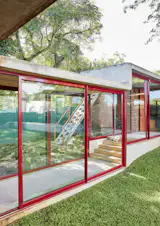 The family cat, Chewbacca, enjoys a moment of sun in one of the glassed-in breezeways. Architect Gregory Katz employed elements of modernism, including extensive glazing, concrete framing, and a flat roof.