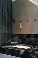 The new primary bathroom includes dramatic silver soapstone countertops and a wall finished in dark glass tile. 