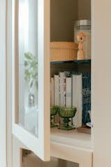 A glass-enclosed module at the end of the bank of kitchen cabinets gives Tomasz and Amy space to display souvenirs from their international travels.