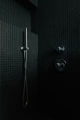 The moody tiled shower in the primary bathroom is homeowner Tomasz Wagner's favorite spot in the home. "I have yelled to Amy, 'I love this shower!' while I'm in there," he admits. 