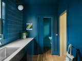 The new addition's laundry area and powder room are awash in shades of blue. Wall paint was color-matched to Fireclay Tile's Blue Velvet tile, and blue grout in a lighter shade corresponds to the all-over color of the powder room.