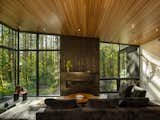 For the living room, Dovetail’s metal shop fabricated a custom fireplace to go between the Quantum windows. The steel surround is coated in an antique black finish to complement the stained cedar wall.