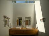 In the primary bathroom, the skylight aligns perfectly with the floating vanity below, letting in an abundance of natural daylight and creating geometric shadows on the walls.