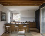 The kitchen's lime-washed ceiling catches the light and added depth to the space, while wood cabinetry and a corrugated backsplash echo the texture and materiality of the home's exterior. The cabinets are from Reform Cabinets. 