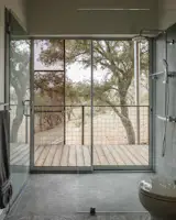 In the primary bathroom, the neutral palette and subtle tile are a play on the surrounding landscape. The clients' acreage provides them with extreme privacy, hence the views from the shower. 