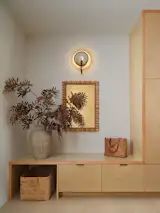 A utilitarian entryway featuring birch cabinetry is softened with an earthenware vase and an ornate mirror. White oak flooring spans the home. 