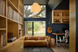 The library doubles as an office for Bhavani's husband. In a mostly white-walled house, the deep, navy-blue paint makes the space feel cozy. The double-wide leather recliner is from Crate & Barrel. The windows purposefully frame the heritage oak tree in the front yard. 