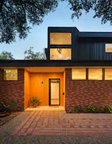 The impactful entry cladding—made from combed Alaskan Yellow Pine—and the custom front door were splurges in the project’s budget. Bhavani calls the back addition a "periscope" because of how it rises above the original home’s footprint.