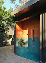 An outdoor shower features two tones of tile from Clay Imports. The smaller, blue squares are the same ones used for the pool's trim. 