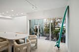 In the dining room, CB2 cozy boucle chairs and a bench in white sit around a white and natural table under a contemporary pendant light. A surfboard is another foundational element to the scene as one of the clients, is an Australian surf enthusiast.