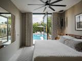 Bedroom, Ceramic Tile Floor, Bed, and Ceiling Lighting A massive floor to ceiling steel pivot door in the primary bedroom adds light and leads to the backyard oasis  Photo 11 of 21 in Historic Phoenix Modern Transformation by Elaina Verhoff