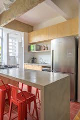 Kitchen, Ceiling Lighting, Refrigerator, Ceramic Tile Floor, Drop In Sink, Cooktops, Concrete Counter, Wood Cabinet, and Ceramic Tile Backsplashe  Photo 10 of 16 in A Renovation Reveals Hardwood Floors and Concrete Beams in This Airy Rio Apartment from General Artigas apartment
