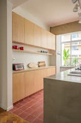 Kitchen, Wall Oven, Cooktops, Concrete Counter, Wood Cabinet, Light Hardwood Floor, and Ceramic Tile Floor  Photo 9 of 16 in A Renovation Reveals Hardwood Floors and Concrete Beams in This Airy Rio Apartment from General Artigas apartment