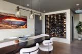 Adjacent to the kitchen, the dining room features dark ceiling that visually compresses the space, encouraging you into the soft bouclé dining chairs. A refrigerated wine room doubles as a display cabinet, the bottles within inspiring the green glass of the Bludot chandelier. 