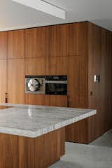 Kitchen, Drop In Sink, Wood Cabinet, Wall Oven, Stone Slab Backsplashe, Concrete Floor, Ceiling Lighting, and Marble Counter  Photo 12 of 15 in House Hh by a2o architecten