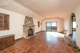Before: original hard wood floor and stone fireplace in the living room with a narrow doorway to the dining room.