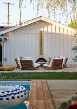 A firepit lounging area featuring a midcentury chiminea stove, plush chairs and crunchy pea gravel underfoot. 