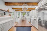 Kitchen, Wine Cooler, Drop In Sink, Cooktops, Accent Lighting, Microwave, Range, Wall Oven, Pendant Lighting, White Cabinet, Ceiling Lighting, Light Hardwood Floor, Refrigerator, and Dishwasher  Photo 2 of 6 in Picturesque Old Village Home by Alexandra Malloy