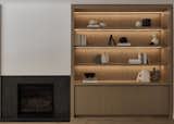 A living room millwork display with integrated LED lighting and a contemporary fireplace with porcelain slab surround.