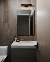A moody modern powder room with dark charcoal and rich wood accents.