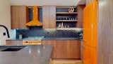 Walnut push to open cabinets, matte black hex tile, and sexy orange appliances