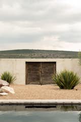 Outdoor, Back Yard, Desert, Concrete Fences, Wall, Shrubs, Grass, and Boulders 150 year old door perfectly accents the valley's rolling hills. It was acquired from a ranch in the valley  Photo 2 of 18 in Fireplaces by Zach Klein from Villa ITO