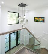 Staircase, Wood Railing, Glass Railing, and Wood Tread Fully renovated double height foyer with new stair and railing design, contemporary light fixture,  wall paneling, as well as new front entry door and windows.  Photo 13 of 21 in Light and Airy by Emilia Ferri