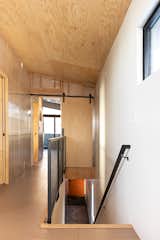 Hallway featuring plywood barn door and ceiling, translucent wall